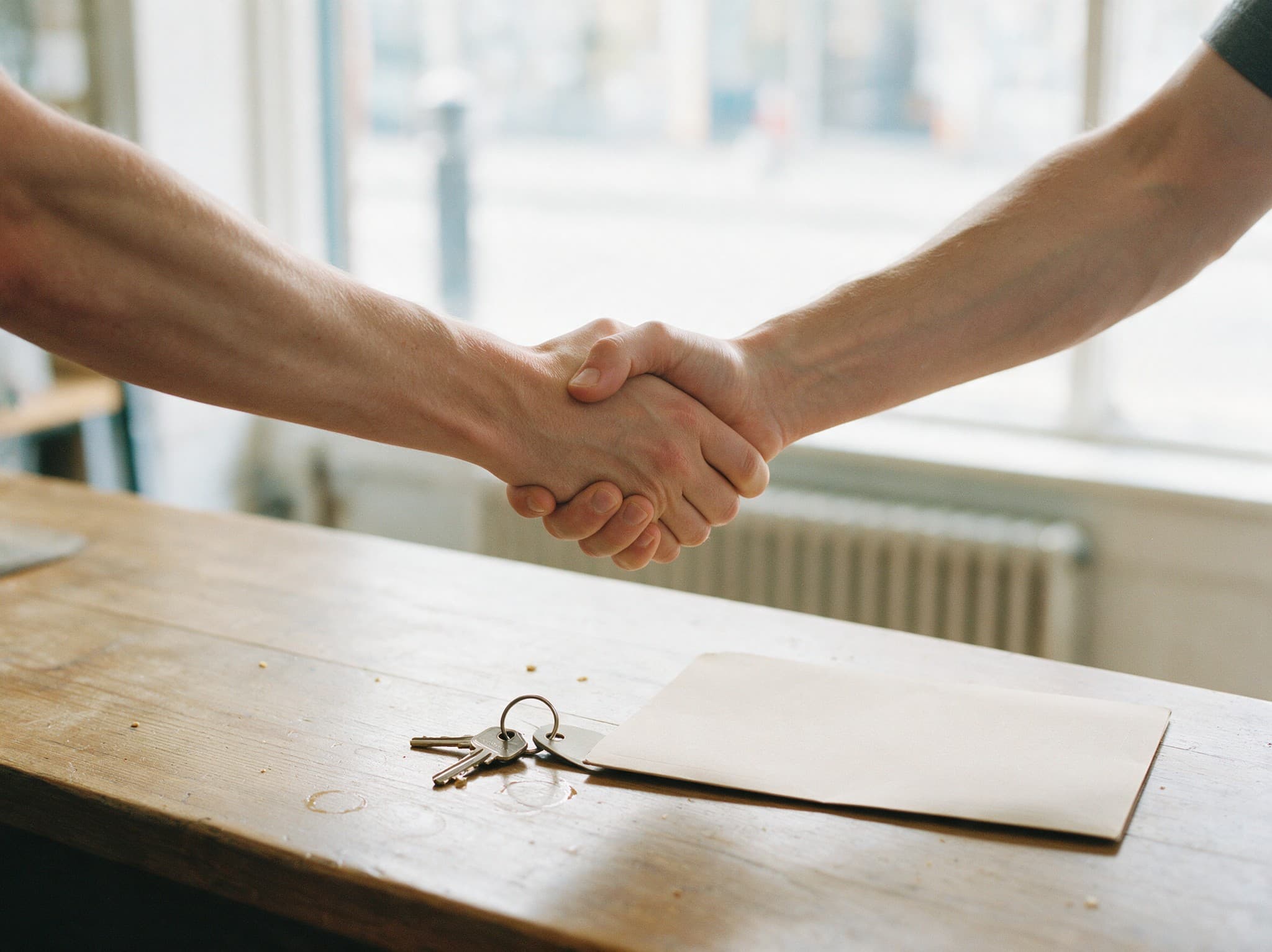 A returning client shaking hands with their estate agent across the branch counter