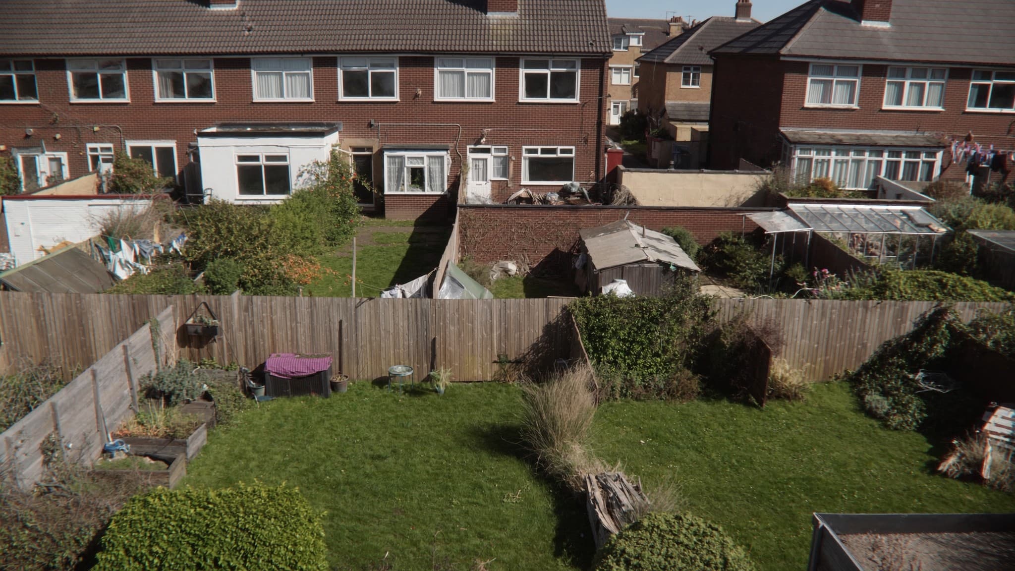 An elevated view over the back gardens of a row of British terraced houses