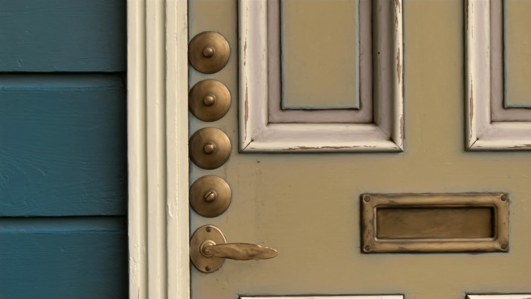 A close view of a painted front door, its brass letterplate, handle and row of bolts