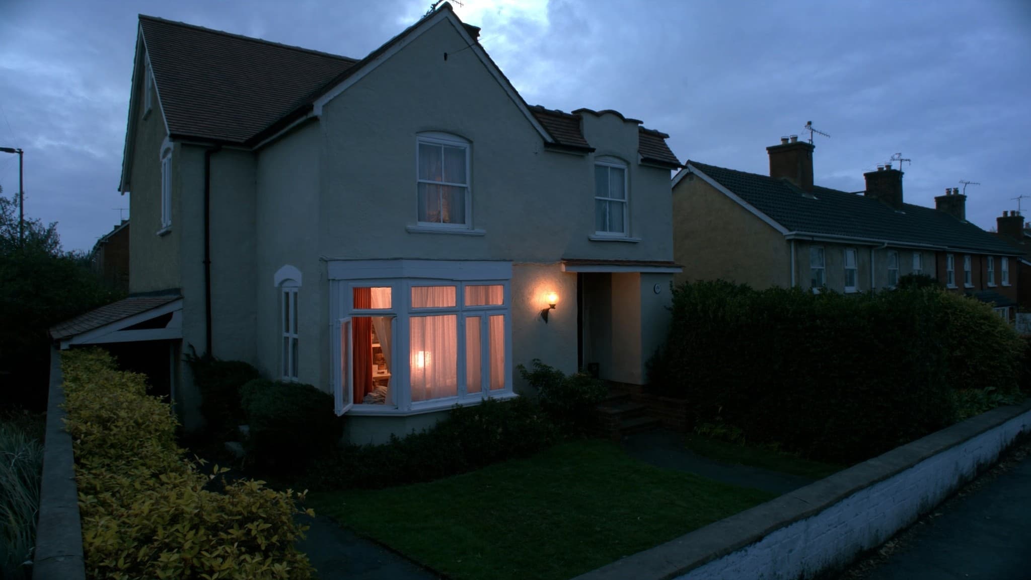 A rendered semi-detached house at dusk with warm light in the front windows