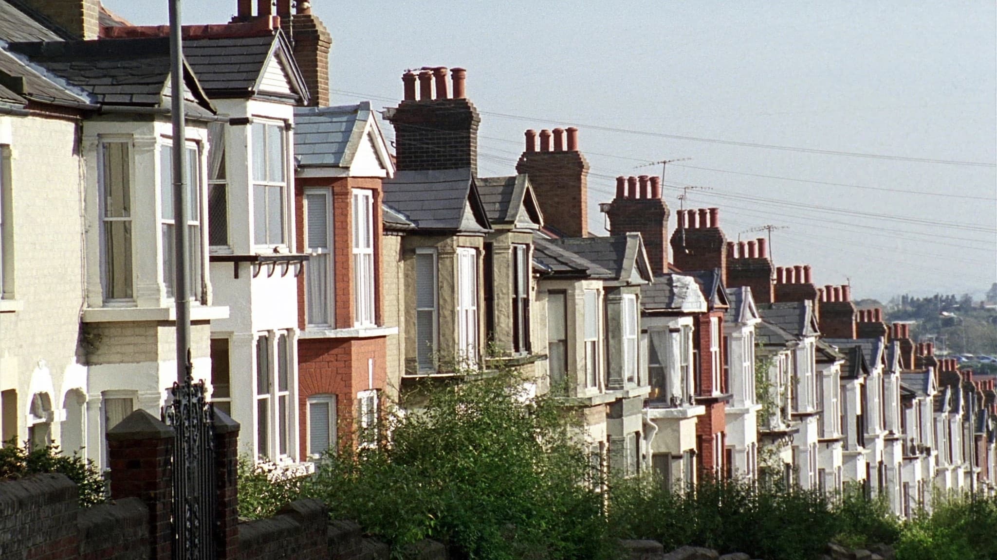 A long terrace of bay fronted houses stepping down a hill, chimney stacks in a line