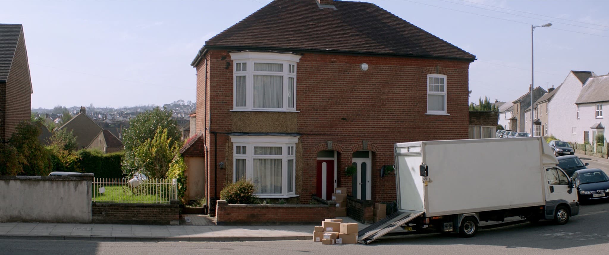 A removals lorry at the kerb outside one house on an otherwise quiet British street