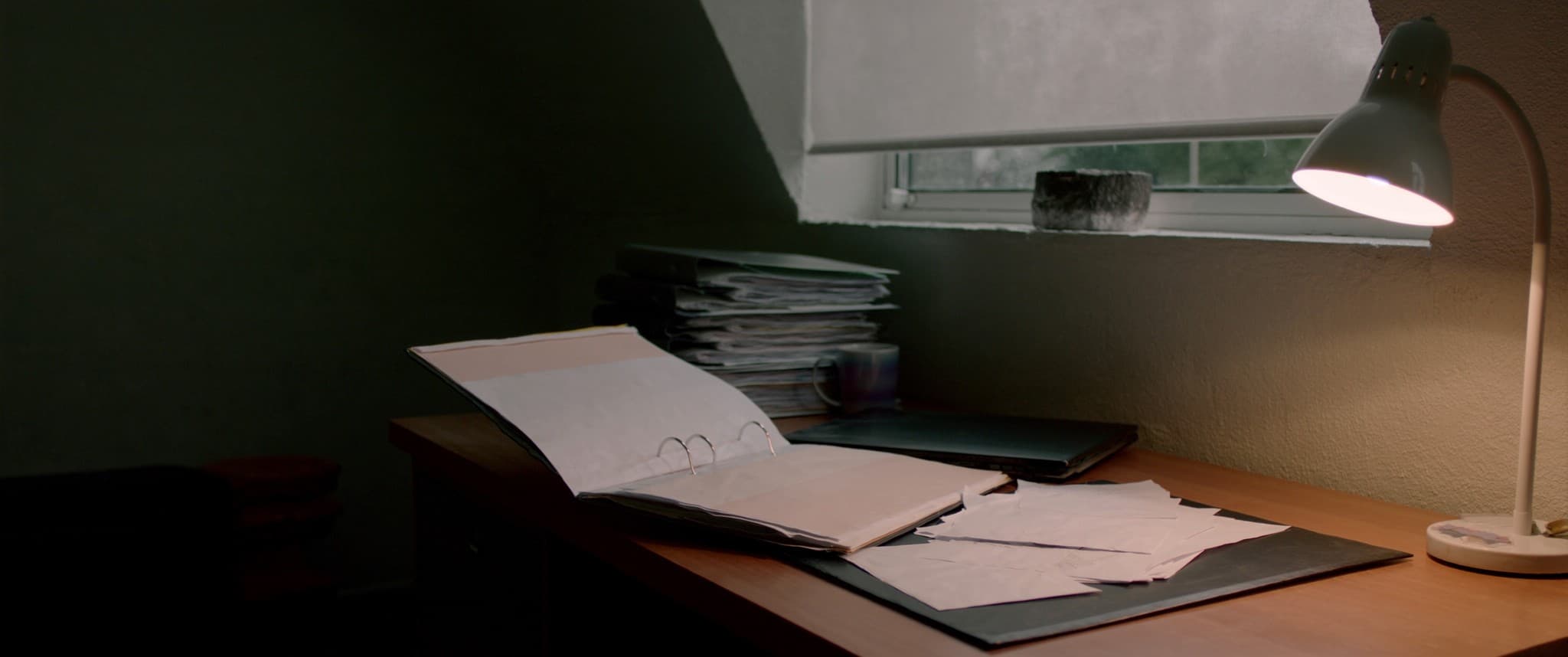 A conveyancer's desk late in the day, an open case file under lamp light.
