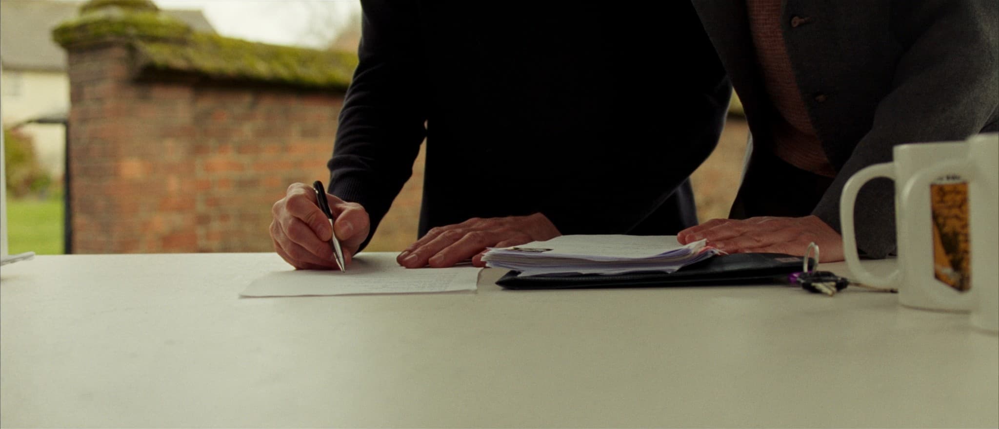 Two people signing paperwork together at a table