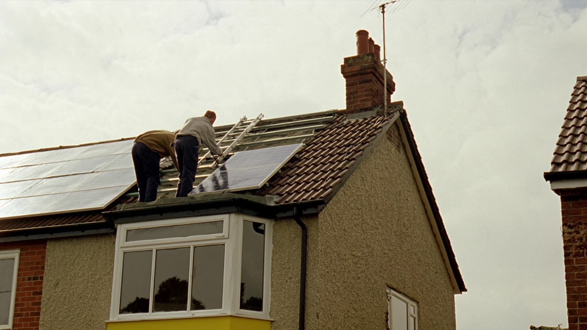 An installer fitting solar panels to the roof of a British home