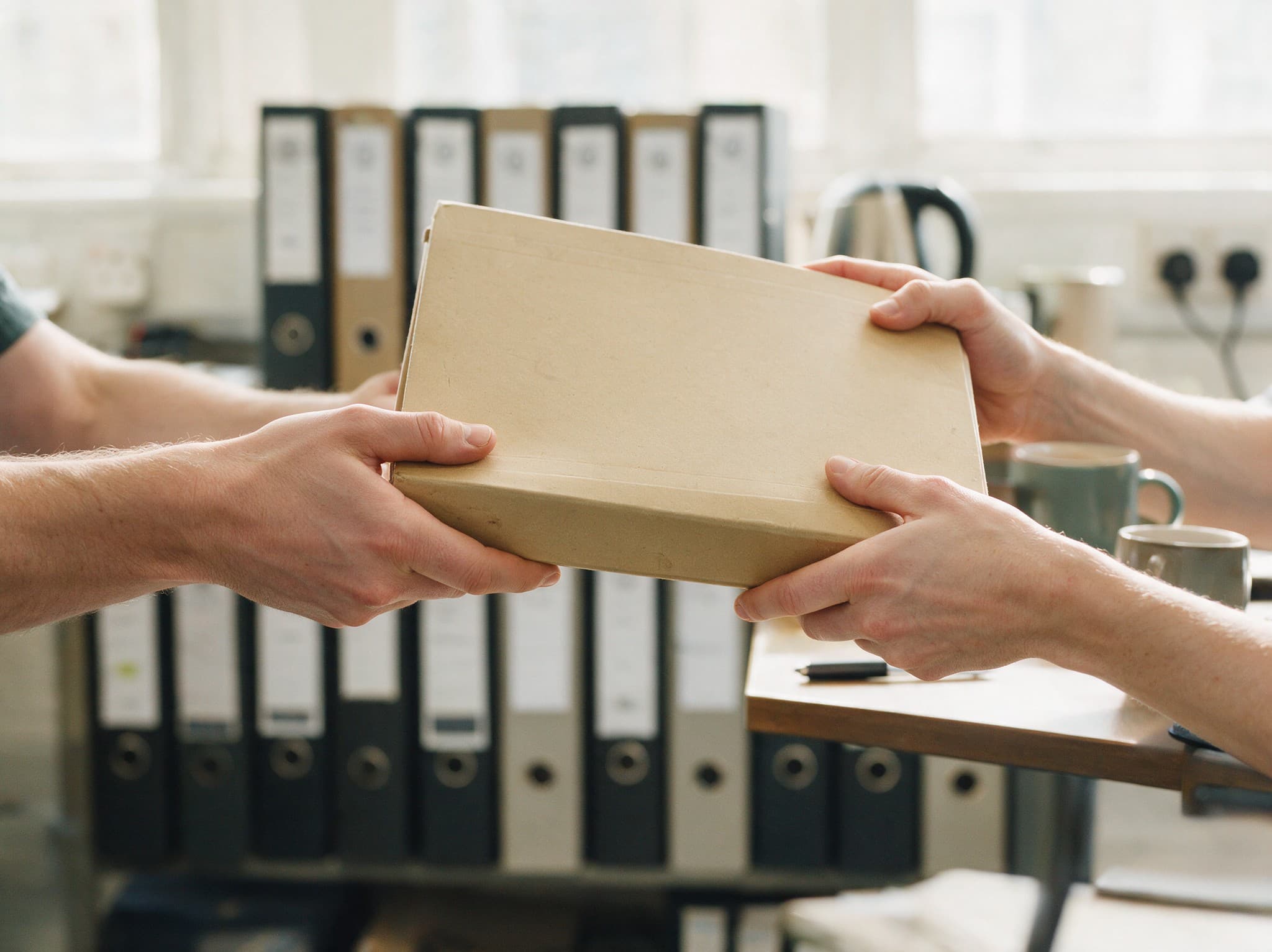 A completed case file being handed across a desk to the conveyancer who will run it