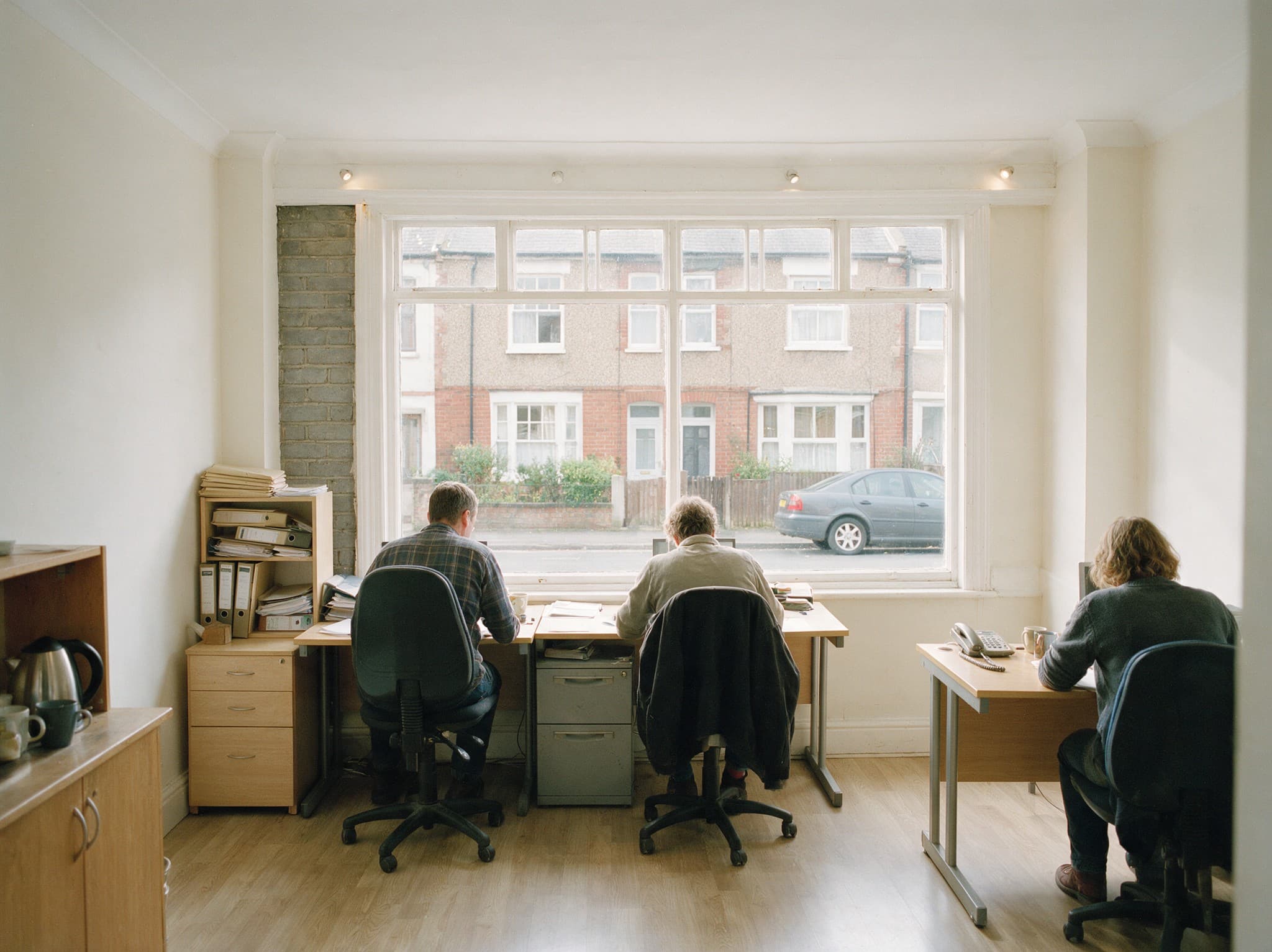 The Home Panel team working at their desks in a small office, case files stacked beside them