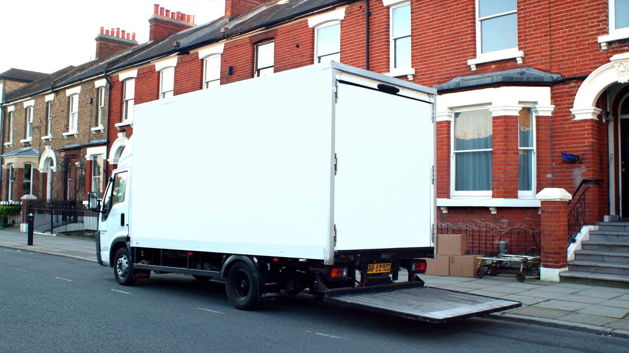 A part-loaded removals van outside one house with another standing open further up the street